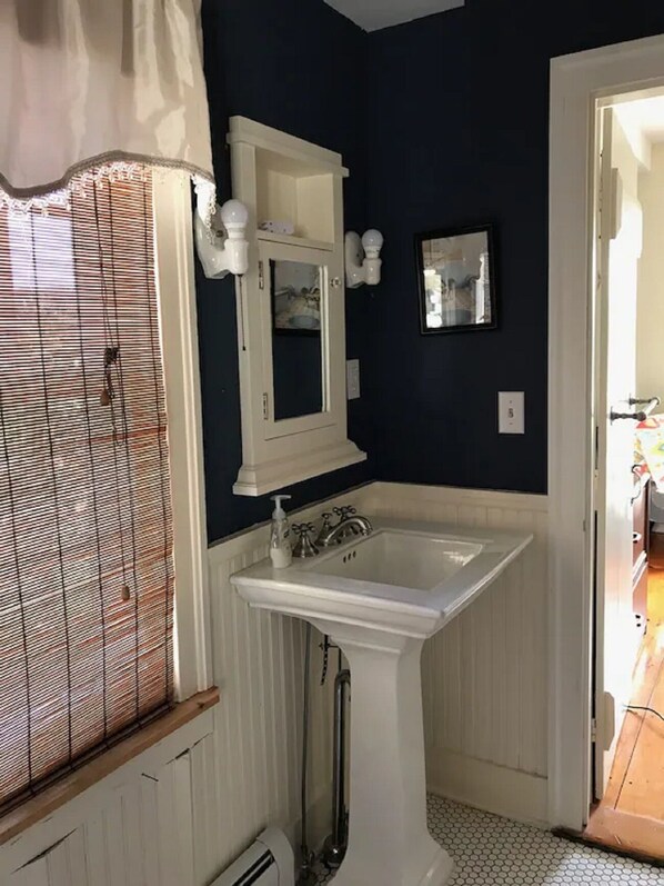 Un baño con lavamanos blanco, espejo y ducha.