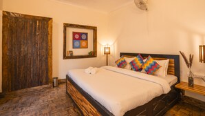 A neatly arranged bedroom with a wooden bed, a framed artwork on the wall, and a bedside table with a vase. - goSTOPS Nainital (Nainital)
