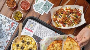 A tray with a pizza, pasta, and condiments on a wooden table. - goSTOPS Nainital (Nainital)