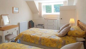 A bedroom with a bed, a dresser, a mirror, a radiator, a window with curtains, and a lamp. - UK35715 - South Cottage (Howpasley, near Hawick)