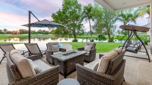 Eine Terrasse im Freien mit Korbmöbeln, einem Tisch und einem Sonnenschirm.