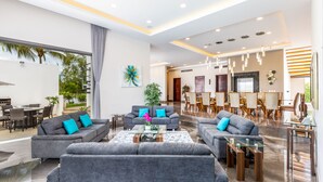 Ein modernes Wohnzimmer mit grauen Sofas, einem Glastisch und einem Essbereich mit Holzstühlen und einem Glastisch.