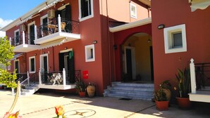 Un edificio rosso con un balcone, una scala e piante in vaso.