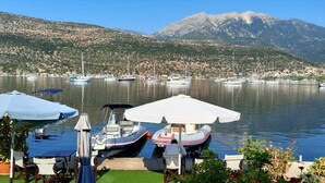 Un porto turistico con barche ormeggiate, un tavolo con sedie e montagne sullo sfondo.
