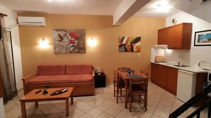Un ambiente compatto con divano, tavolo da pranzo e angolo cottura.