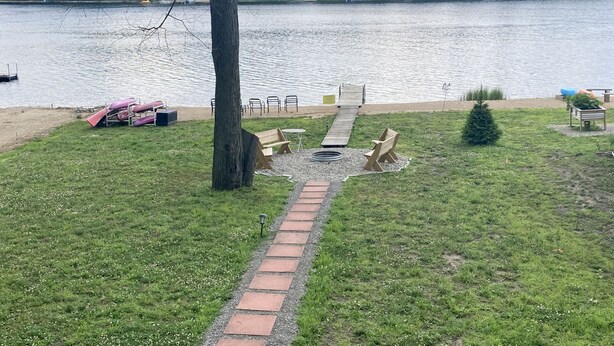 A lakeside park with a wooden deck, picnic tables, and a small Christmas tree. - Lake House on Jose Lake (South Branch)