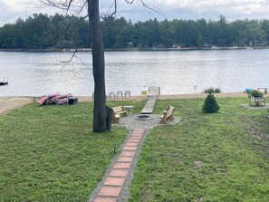 Un parque junto al lago con un muelle de madera, mesas de picnic y un pequeño árbol de Navidad.