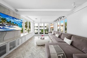 Ein geräumiges Wohnzimmer mit großem Fernseher, einer Couch und einem Couchtisch.