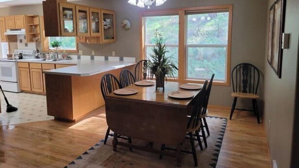 A modern kitchen with wooden cabinets, a central island, and a dining area with a table and chairs. - Secluded Montana home on five acres (Rexford)