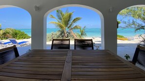 A wooden table with a view of a beach through an arched window.