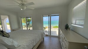 A bedroom with a bed, a ceiling fan, a dresser, and a view of the beach. - Caicos Cottage, 2bd/2bath Beachfront Villa w/pool on Whitby Beach (Caicos Islands)