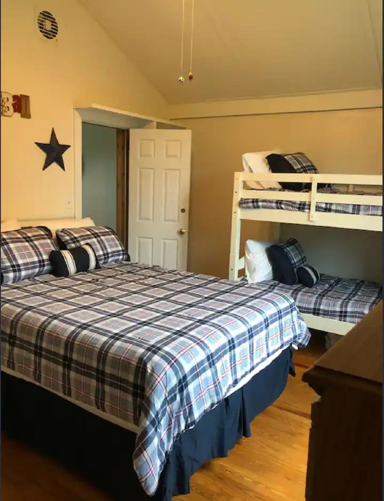 Une chambre avec un lit, deux lits superposés, une décoration sur le thème des étoiles et une porte.