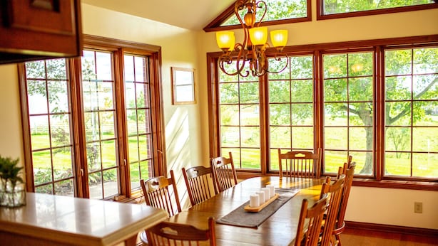 A dining area with a large wooden table, multiple chairs, and a chandelier. - Holland Acres (Williamstown)