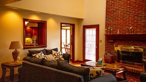 A living room with a sofa, a lamp, a fireplace, and a dining area with chairs. - Holland Acres (Williamstown)