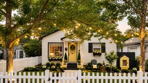 A white house with a yellow door, a white picket fence, and string lights. - Peaceful & Cozy Home - Fenced Yards - North End (Boise)