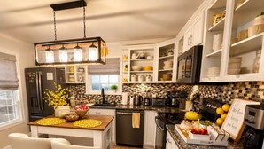 A modern kitchen with white cabinetry, a central island, stainless steel appliances, and a decorative backsplash. - Peaceful & Cozy Home - Fenced Yards - North End (Boise)