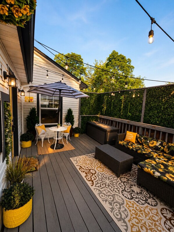 Une terrasse dotée de mobilier d’extérieur, d’une table et de guirlandes lumineuses.