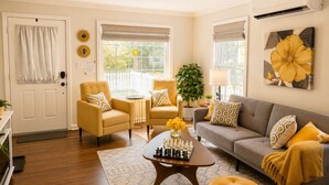 A living room with a sofa, two armchairs, a coffee table with chess pieces, a potted plant, and a large flower painting on the wall. - Peaceful & Cozy Home - Fenced Yards - North End (Boise)