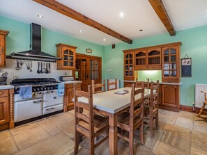Une cuisine avec des meubles de rangement en bois, une cuisinière et une table à manger avec des chaises.