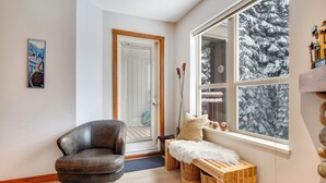 Ein modernes Zimmer mit Ledersessel, Holzbank und einem großen Fenster mit Blick auf Schnee.