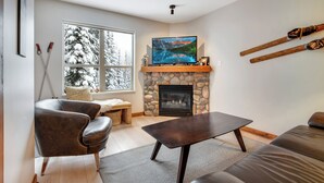 Ein Wohnzimmer mit Kamin aus Stein, einem Fernseher und an der Wand befestigten Skiern.