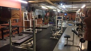 Ein Fitnessstudio mit verschiedenen Trainingsgeräten, darunter Kraftgeräte und Kurzhanteln.