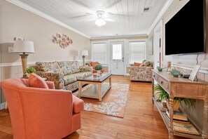 A living room with a sofa, armchair, coffee table, and a television. - Charming & Fun! Vacation home w/private pool, game room, short stroll to beach-perfect for families (North Myrtle Beach)