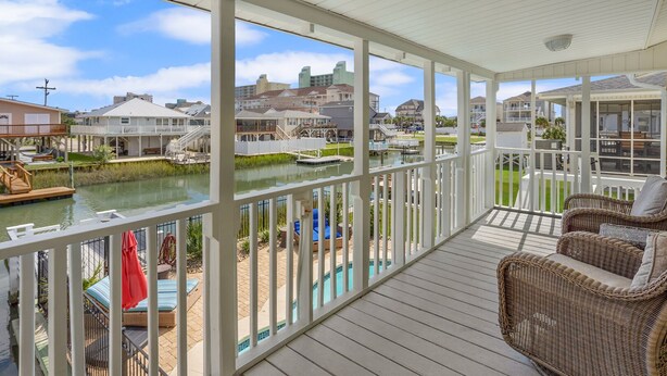 A covered outdoor deck with a view of a marina and buildings in the background. - Updated Family-friendly channel home with private pool & close to the beach (North Myrtle Beach)
