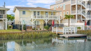 A waterfront residential building with a dock, a covered patio, and a small garden area. - Updated Family-friendly channel home with private pool & close to the beach (North Myrtle Beach)