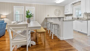 A modern kitchen with white cabinetry, a wooden dining table, and bar stools. - Updated Family-friendly channel home with private pool & close to the beach (North Myrtle Beach)