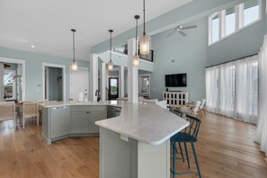 A spacious kitchen with a central island, pendant lighting, and a dining area with chairs.