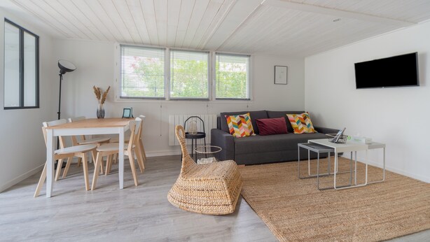 Een moderne woonkamer met een eettafel, bank en televisie.