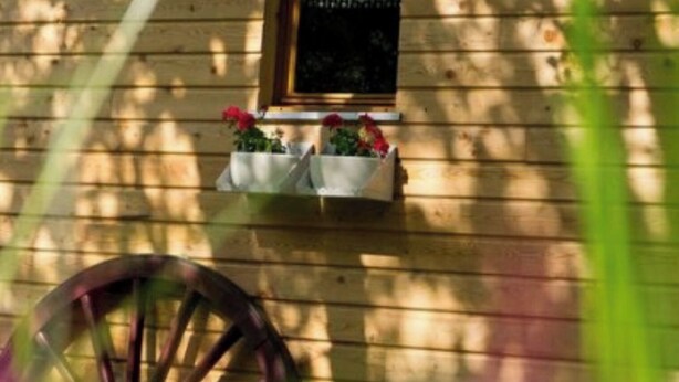 Un bâtiment en bois doté d’une fenêtre et d’une roue en bois.