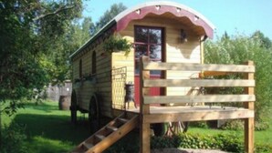 Une structure en bois avec une rampe menant à une porte, le tout entouré de verdure.