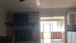 A living room with a fireplace, a sofa, a coffee table, and a sliding glass door leading to an outdoor area. - Lakefront Retreat At Randolphs Landing (Mannng)