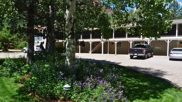 En byggnad med ett takförsett parkeringsområde och en trädgård med lila blommor.