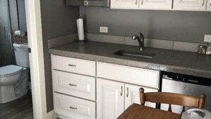 Une cuisine compacte avec des meubles blancs, un four à micro-ondes, un évier et une table à manger.