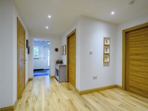 Un pasillo con suelo de madera, paredes blancas y puertas de madera.