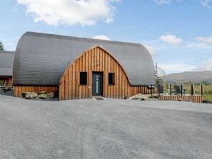 Un edificio de estilo granero, de madera, con techo inclinado, una puerta principal y una pequeña ventana.