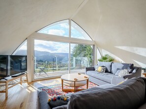 Ein modernes Wohnzimmer mit einem großen Schiebeglasfenster, einem Sofa, einem Couchtisch und einem Fernseher.