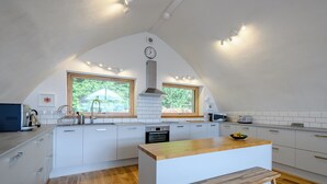 A modern kitchen with white cabinetry, a wooden island, and a large window.