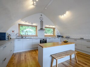 A modern kitchen with white cabinetry, a wooden island, and a large window. - Jack Strawbale House - UK7521 (Strontian, near Fort William)