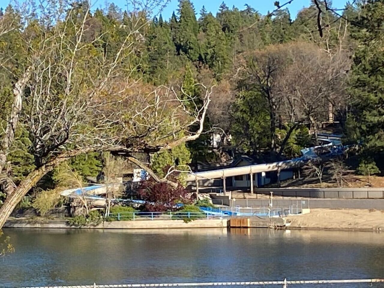 Une propriété au bord du lac, dotée d’un quai abrité, d’un bâtiment à toit en pente et d’une forêt dense en arrière-plan.