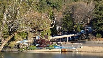 Une propriété au bord du lac, dotée d’un quai abrité, d’un bâtiment à toit en pente et d’une forêt dense en arrière-plan.
