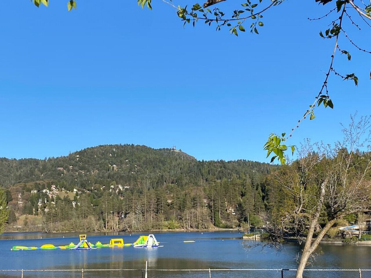 A lake with boats and a forested hill in the background.