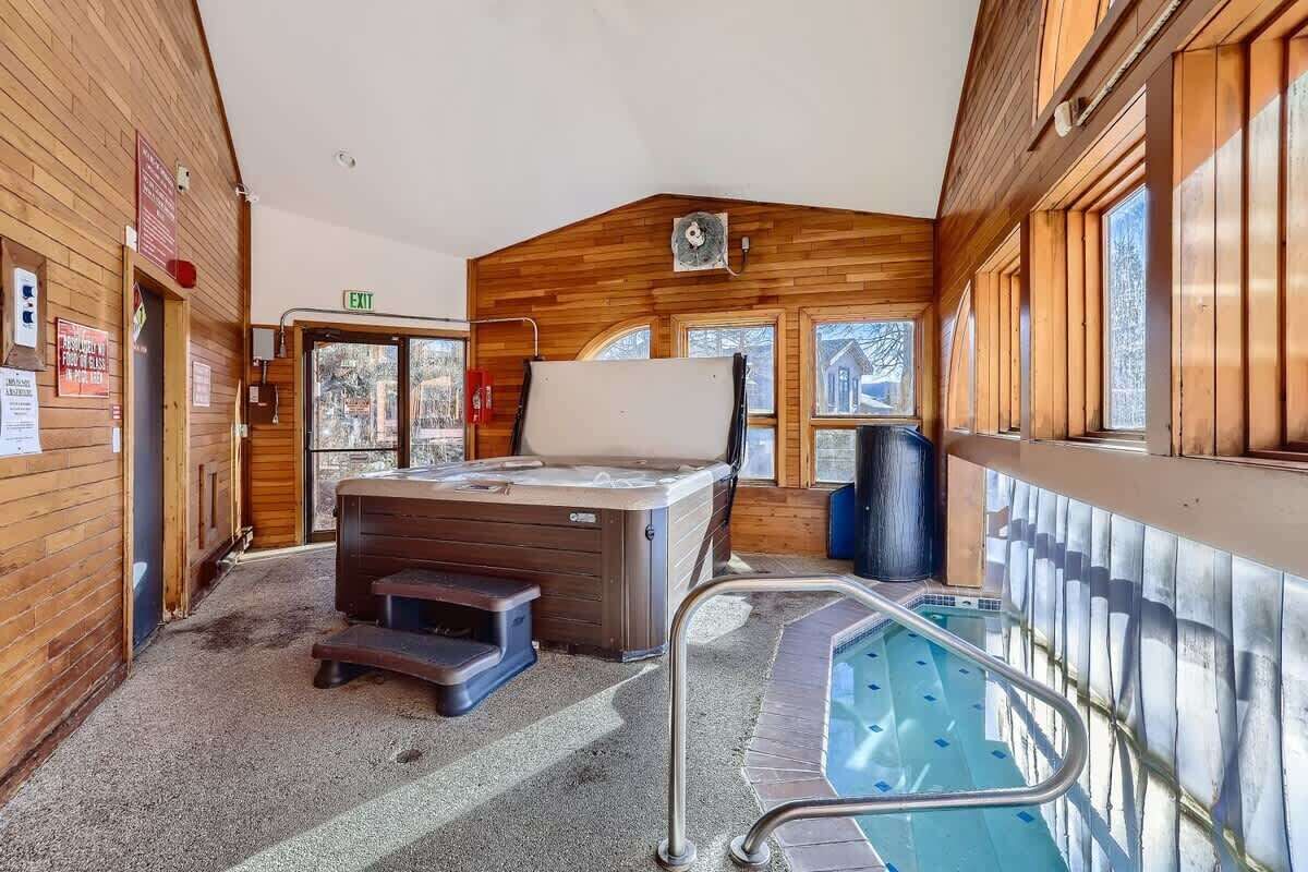 Un intérieur en bois avec un jacuzzi, une piscine et un panneau de signalisation indiquant la sortie.