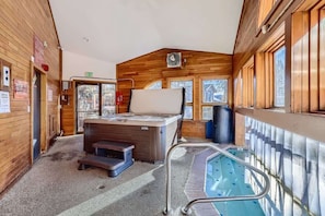 A wooden interior with a hot tub, a pool, and an exit sign.