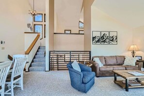 A spacious living room with a staircase, a dining area, and a sofa.