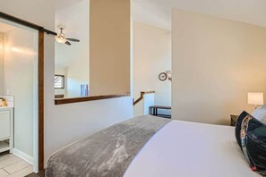 Une chambre d’hôtel avec un lit, un ventilateur de plafond, un vélo en arrière-plan et un miroir au mur.