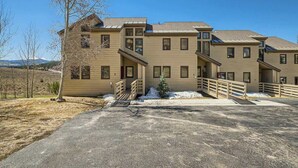A multi-story building with a symmetrical facade, a covered driveway, and a small tree in the foreground.
